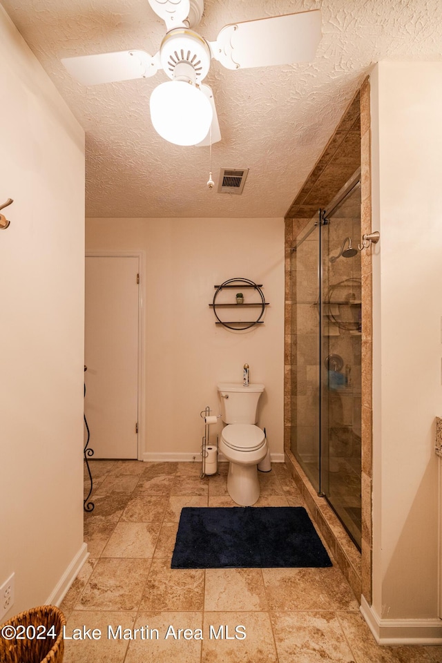 bathroom featuring ceiling fan, a shower with shower door, a textured ceiling, and toilet