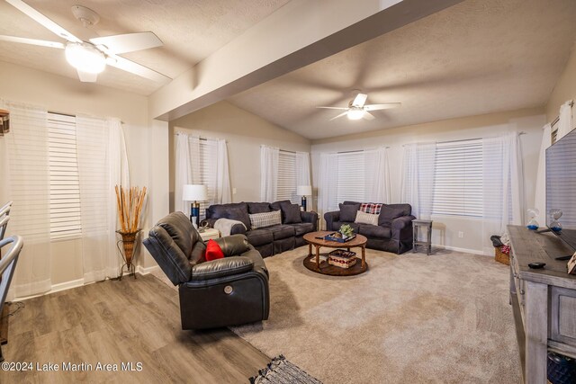 living room featuring a textured ceiling, ceiling fan, light hardwood / wood-style flooring, and vaulted ceiling