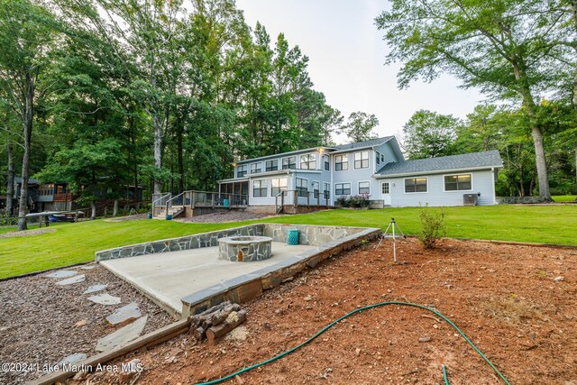 rear view of house featuring a lawn, a patio area, and an outdoor fire pit