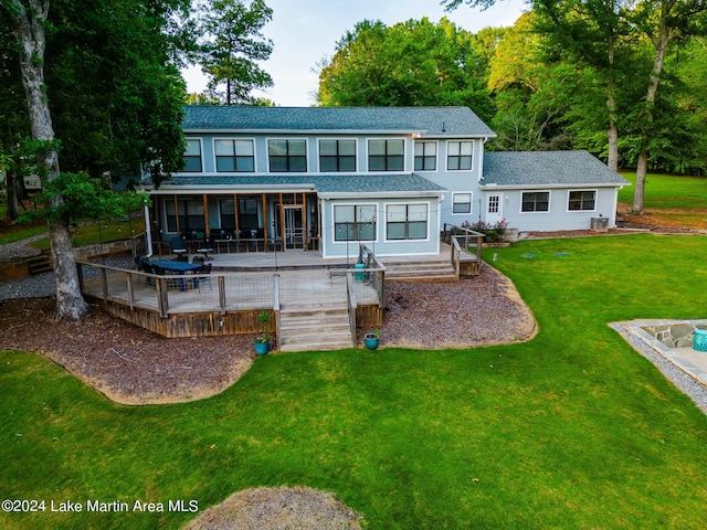 rear view of property featuring a sunroom, a deck, and a yard