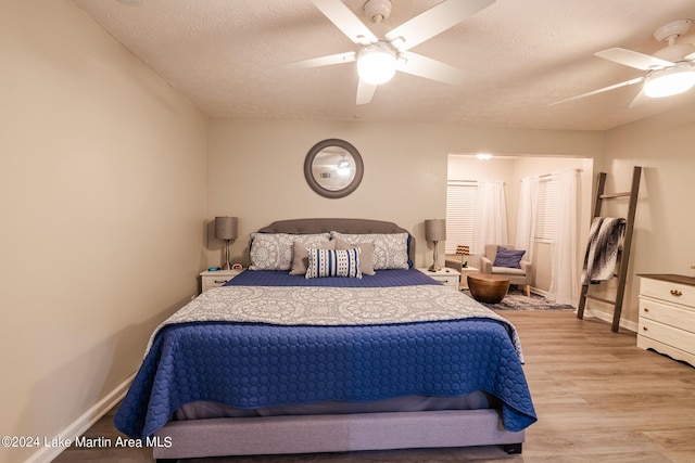 bedroom with a textured ceiling, light wood-type flooring, and ceiling fan