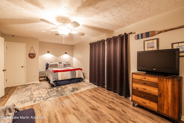 bedroom with ceiling fan, light hardwood / wood-style floors, and a textured ceiling