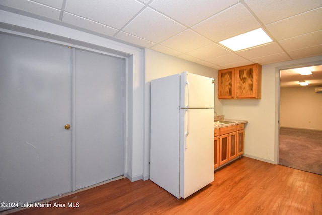 kitchen with a drop ceiling, white fridge, and light hardwood / wood-style floors