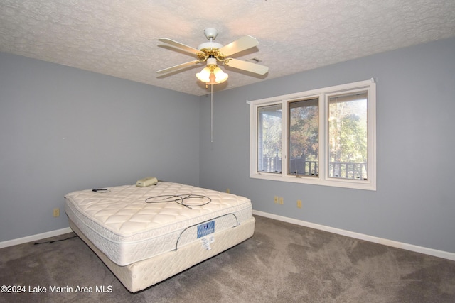 bedroom featuring a textured ceiling, dark carpet, and ceiling fan