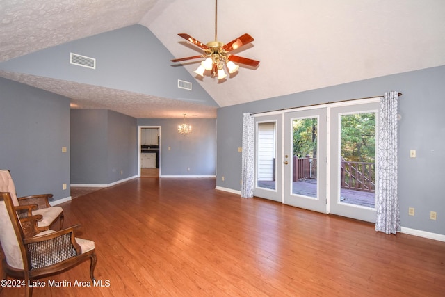 living room featuring hardwood / wood-style floors, ceiling fan with notable chandelier, a textured ceiling, and high vaulted ceiling