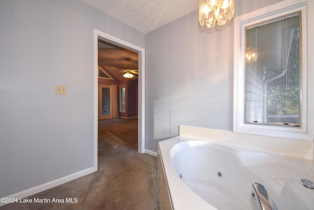 bathroom featuring a tub to relax in, ceiling fan with notable chandelier, and a textured ceiling