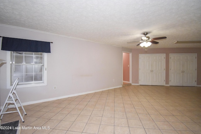 tiled empty room featuring ceiling fan and a textured ceiling