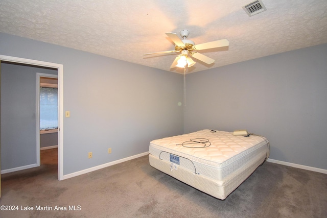 carpeted bedroom featuring ceiling fan and a textured ceiling