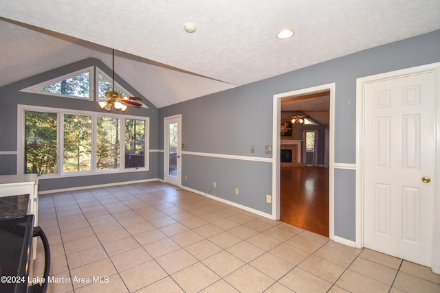 interior space featuring a textured ceiling, vaulted ceiling, ceiling fan, and light tile patterned flooring