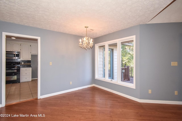 spare room featuring hardwood / wood-style floors, a chandelier, and a textured ceiling