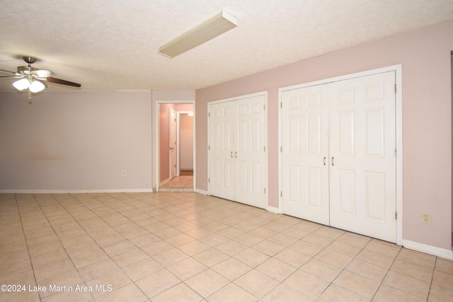 unfurnished bedroom with multiple closets, ceiling fan, and light tile patterned flooring