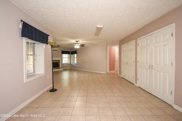 interior space featuring ceiling fan, light tile patterned floors, and a textured ceiling