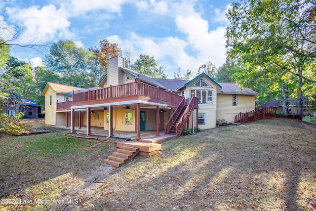 back of property with a deck, ceiling fan, a patio area, and a lawn