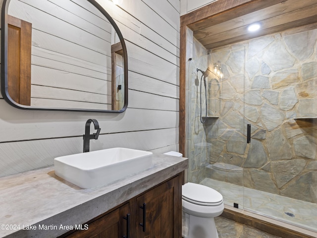 bathroom featuring vanity, toilet, a shower with shower door, and wooden walls