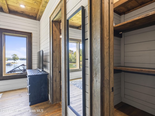 interior space featuring wood ceiling, wooden walls, a water view, and wood-type flooring