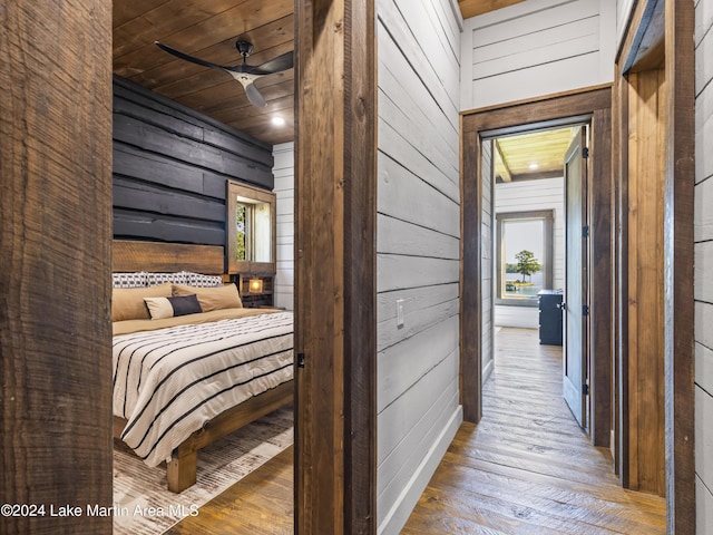 unfurnished bedroom with wood ceiling, multiple windows, wooden walls, and wood-type flooring