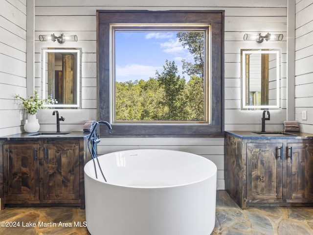 bathroom featuring a washtub, vanity, and wooden walls