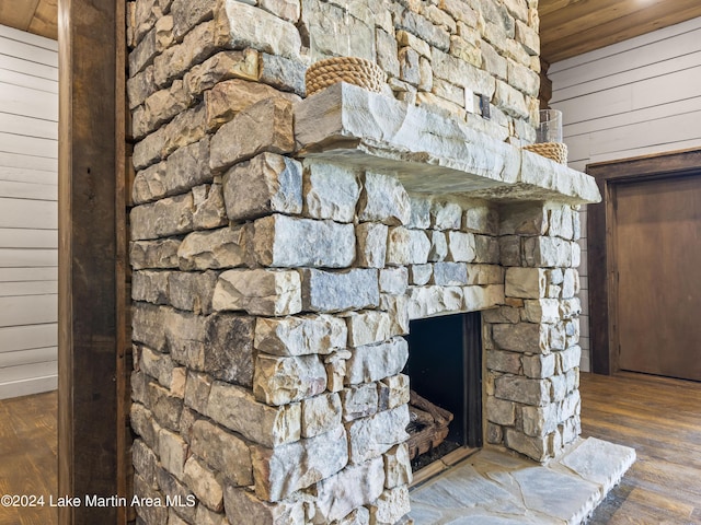 interior details with hardwood / wood-style floors, a stone fireplace, and wooden walls