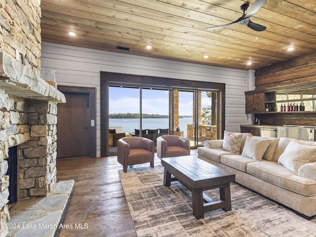 living room featuring wood-type flooring, a water view, wooden ceiling, a fireplace, and wood walls