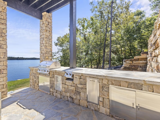 view of patio featuring an outdoor kitchen, area for grilling, and a water view