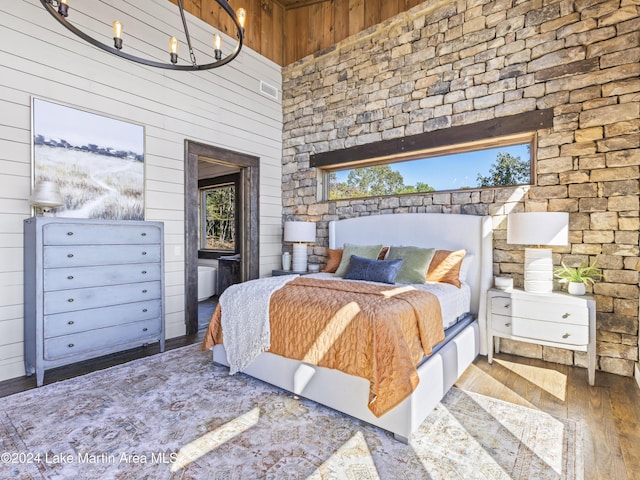 bedroom featuring hardwood / wood-style floors, wood walls, and a high ceiling