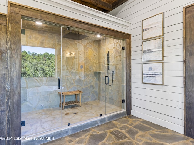 bathroom featuring wood walls and a shower with shower door