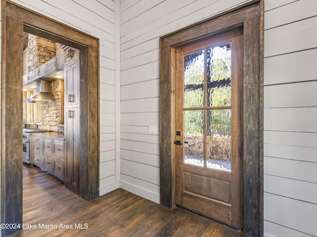 doorway to outside featuring wood walls and dark wood-type flooring