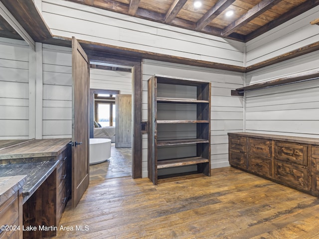 walk in closet with beamed ceiling and dark wood-type flooring