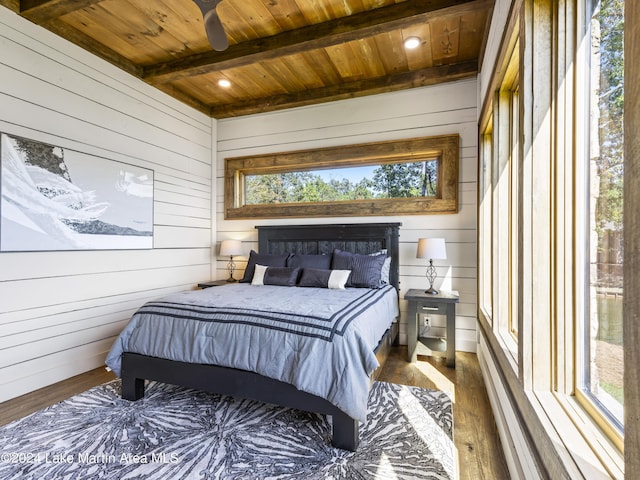 bedroom with beam ceiling, dark hardwood / wood-style floors, wooden walls, and wood ceiling