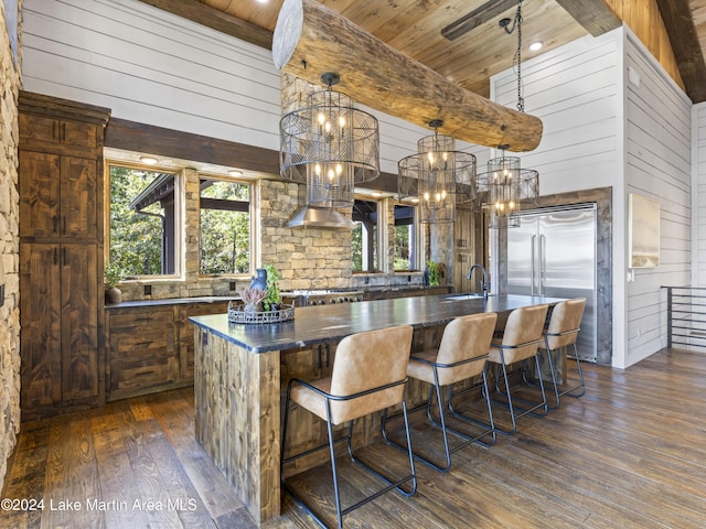 kitchen featuring wood walls, plenty of natural light, a kitchen island with sink, and appliances with stainless steel finishes