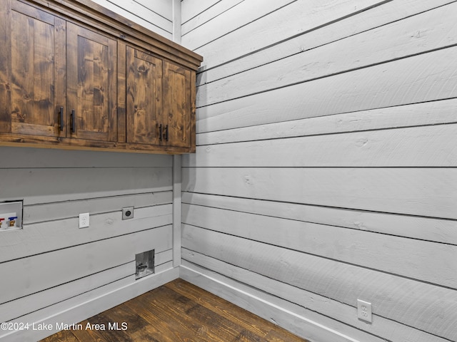 clothes washing area featuring cabinets, washer hookup, dark hardwood / wood-style floors, and wooden walls