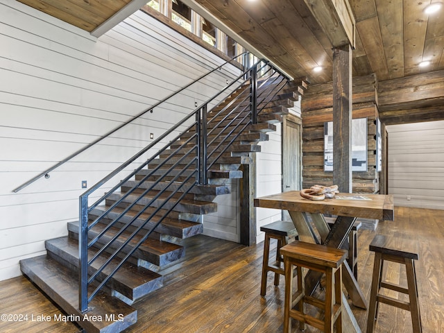 stairway featuring hardwood / wood-style floors, wooden ceiling, and wooden walls