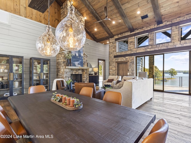 dining room with wooden ceiling, high vaulted ceiling, beamed ceiling, light hardwood / wood-style floors, and a fireplace