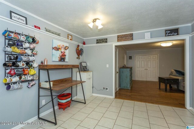 interior space with a textured ceiling, light hardwood / wood-style floors, and ornamental molding