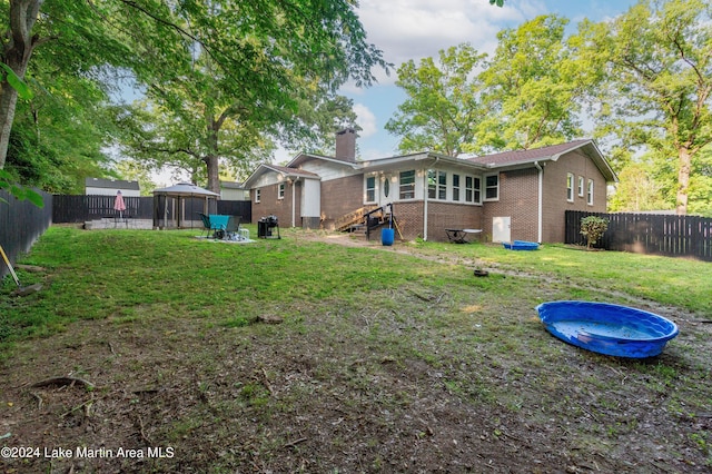 rear view of property with a gazebo and a yard