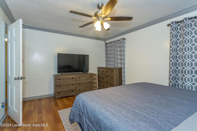 bedroom with ceiling fan, crown molding, wood-type flooring, and a textured ceiling