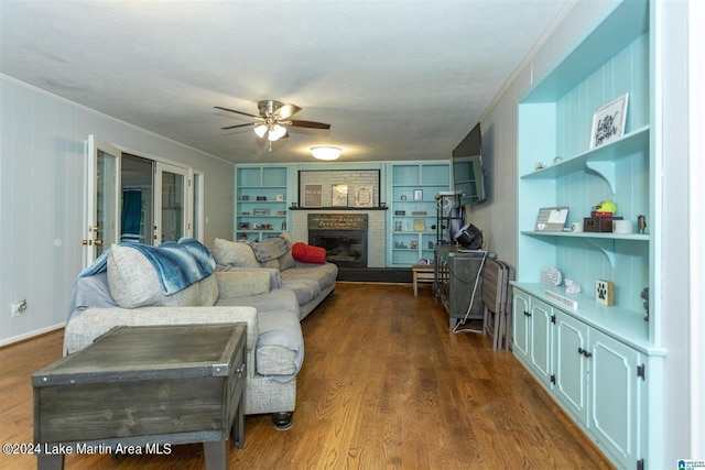 living room featuring french doors, ornamental molding, ceiling fan, a fireplace, and dark hardwood / wood-style floors