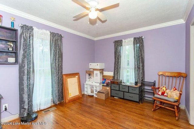 interior space featuring ceiling fan, ornamental molding, a healthy amount of sunlight, and hardwood / wood-style flooring