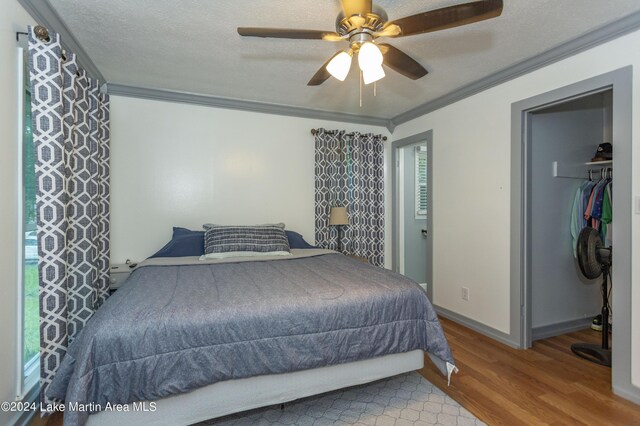 bedroom with light wood-type flooring, ornamental molding, a textured ceiling, ceiling fan, and a closet