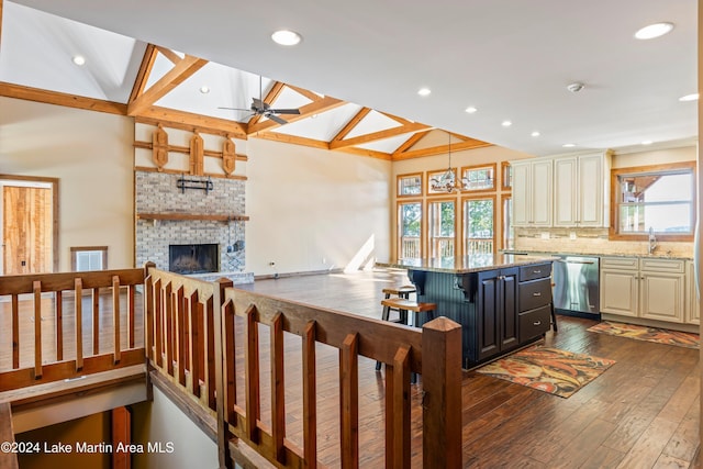 kitchen with tasteful backsplash, dishwasher, light stone counters, cream cabinets, and dark wood-style floors