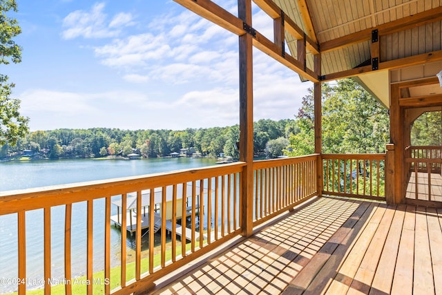 wooden deck featuring a wooded view and a water view