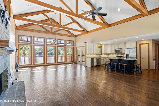 living room featuring ceiling fan with notable chandelier, dark wood-style floors, plenty of natural light, and a fireplace