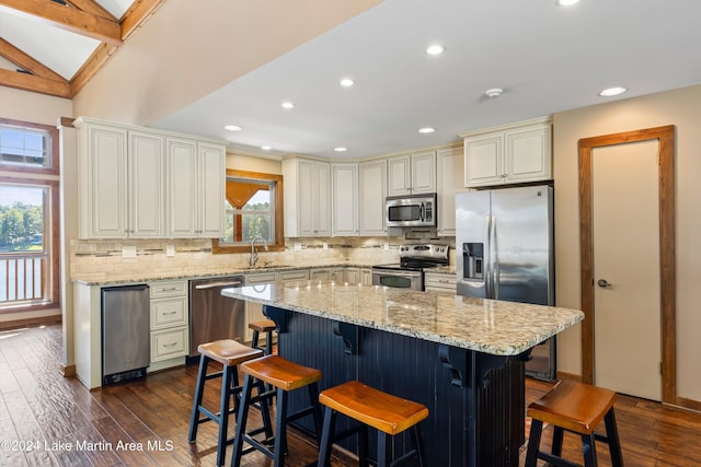 kitchen featuring a sink, tasteful backsplash, dark wood finished floors, stainless steel appliances, and light stone countertops