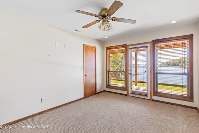 empty room featuring visible vents, baseboards, light colored carpet, and ceiling fan