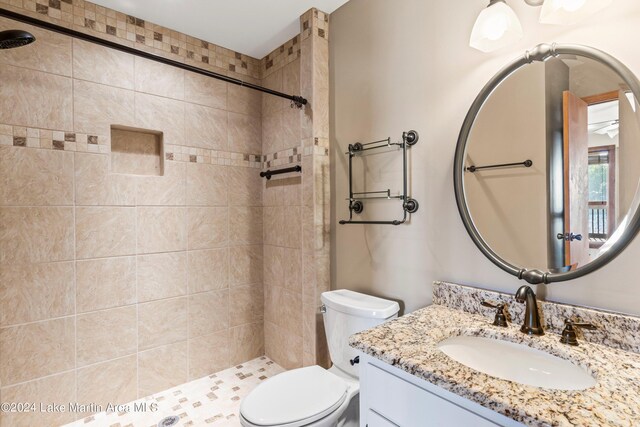 bathroom featuring toilet, vanity, and a tile shower