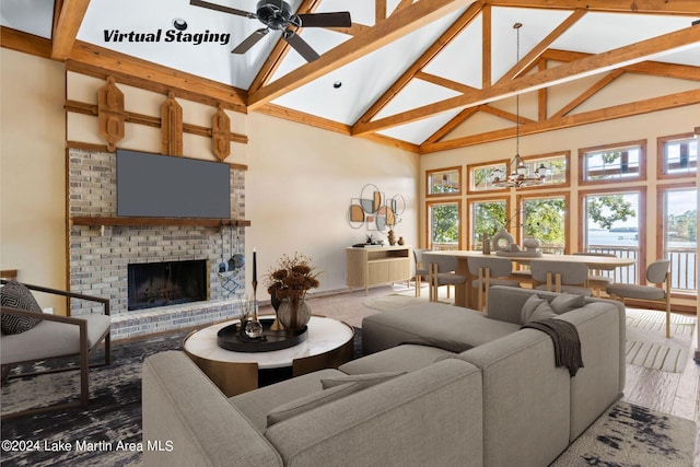 living room featuring a wealth of natural light, ceiling fan with notable chandelier, a brick fireplace, and high vaulted ceiling