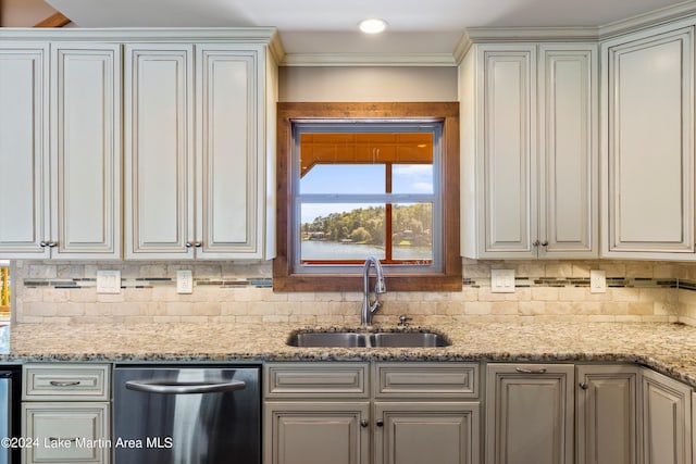 kitchen featuring a sink, light stone counters, backsplash, and stainless steel dishwasher