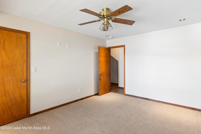 spare room featuring baseboards, light colored carpet, and a ceiling fan