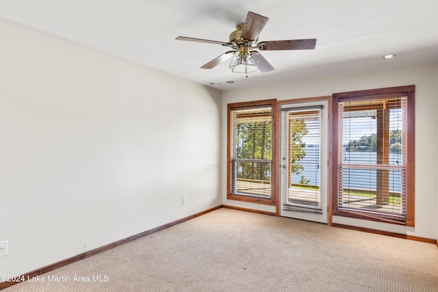 empty room featuring light carpet, ceiling fan, and baseboards