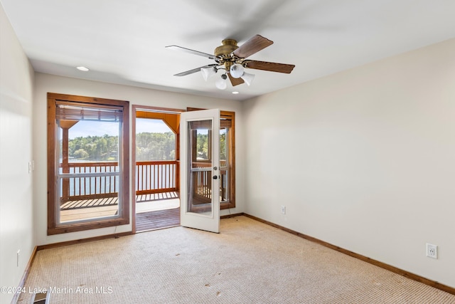 carpeted spare room with a ceiling fan, baseboards, and french doors